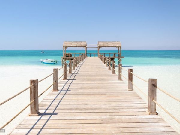 A wooden pier extending into the turquoise waters of Hurghada with a clear blue sky overhead