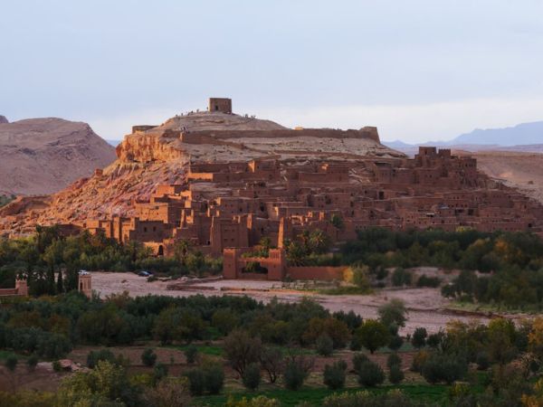 historic village built into a hill, glowing warmly under the evening light surrounded by lush greenery