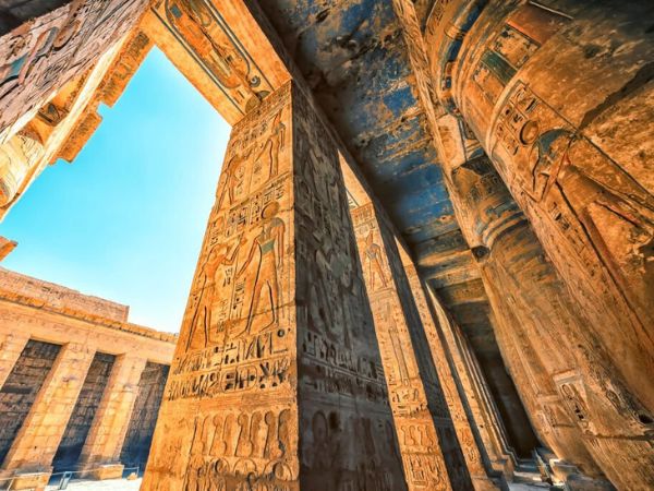 Ancient columns with detailed carvings in the temples of Luxor, illuminated by the bright sun