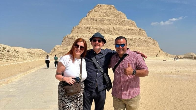 Three tourists posing in front of the Step Pyramid of Djoser at Saqqara, Egypt