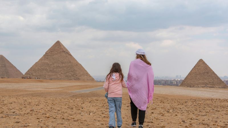 Two women walking hand in hand near the Pyramids of Giza