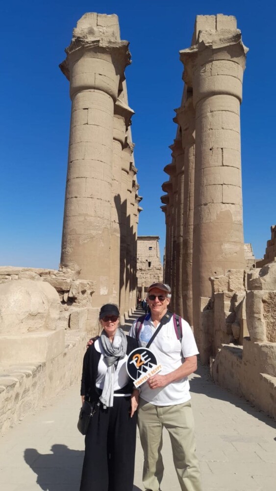 A couple standing in front of towering stone columns at an ancient Egyptian temple