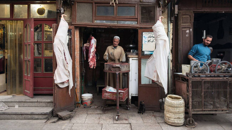 A butcher’s display featuring freshly cut meat hanging on hooks in a traditional market