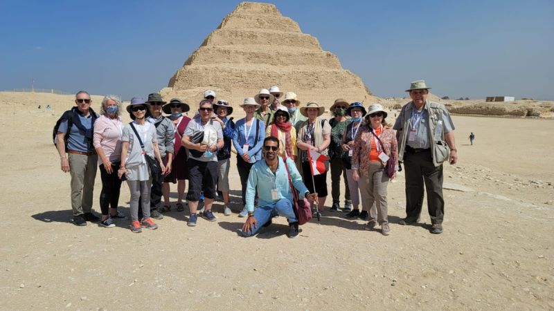 A group of tourists posing in front of the Step Pyramid of Saqqara in Egypt