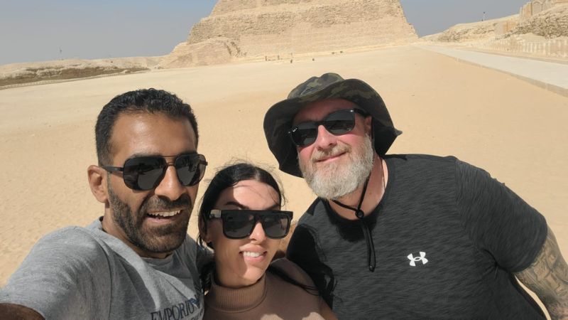 A group of tourists taking a selfie in front of the Step Pyramid of Saqqara