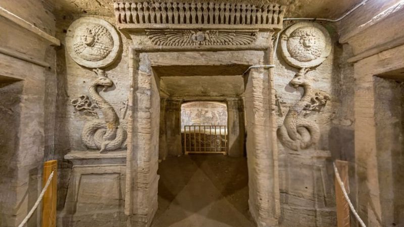 Entrance to the Catacombs of Kom El Shoqafa in Alexandria adorned with ancient serpent motifs carved into the stone