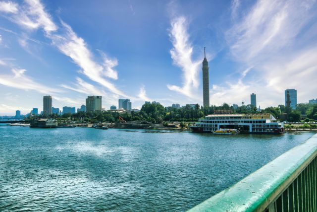 A panoramic view of Cairo’s modern skyline with the Nile River flowing through the city under a clear, vibrant sky