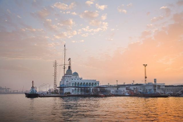 mosque with blue domes on the waterfront at sunset