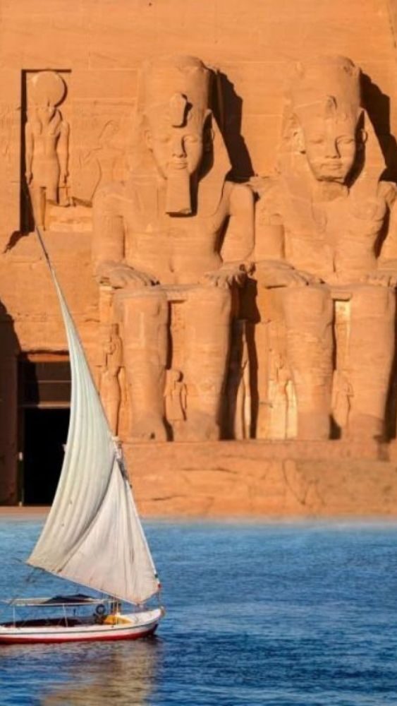 The Great Temple of Abu Simbel in Egypt with four colossal statues of Pharaoh Ramses II seated at the entrance carved into a sandstone cliff under a clear blue sky