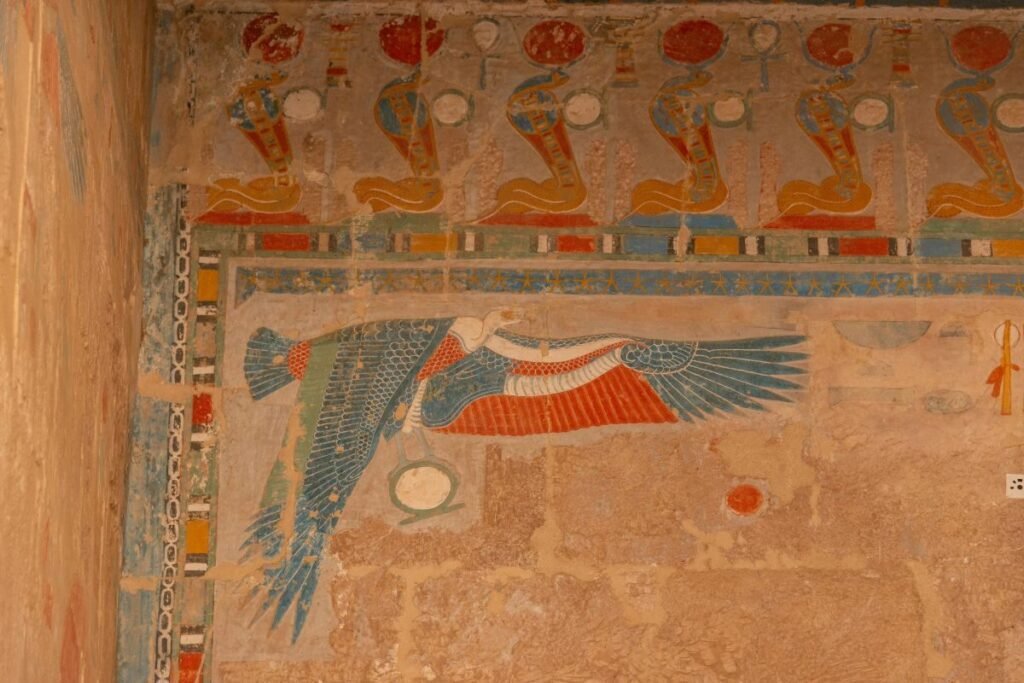 Wall painting of vulture goddess Nekhbet flying beneath crowned cobra symbols