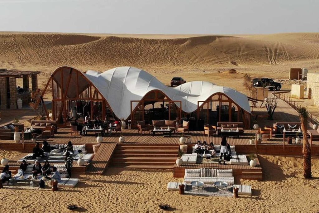Stylish desert glamp site with outdoor seating and sand dune backdrop