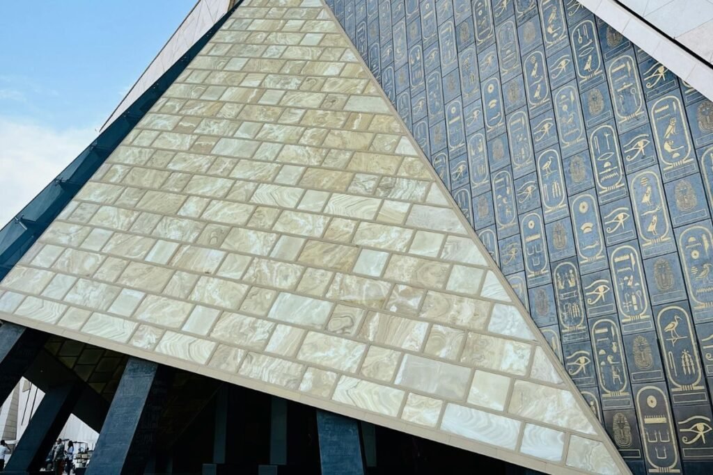 grand egyptian museum entrance with pyramid design and hieroglyphic inscriptions