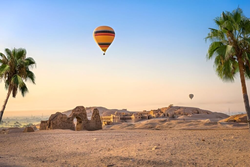 hot air balloon flying over ancient ruins and desert landscape in Luxor Egypt