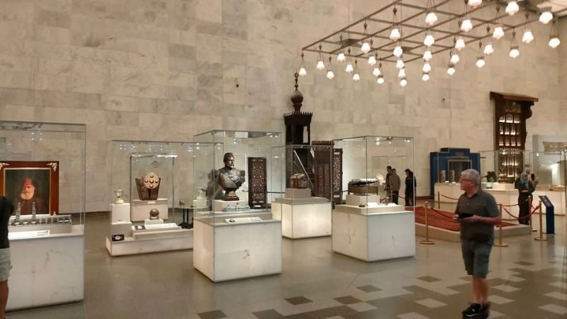 Museum gallery with illuminated display cases showing ancient Egyptian artifacts and pottery