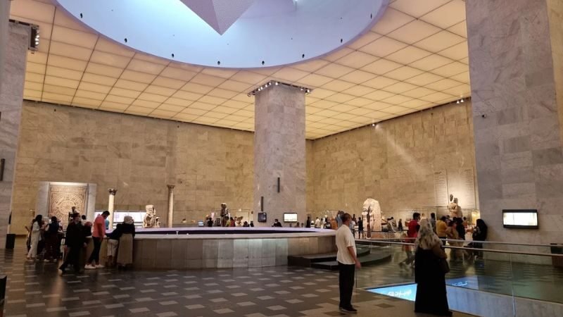 Grand modern museum atrium with sleek architecture and ancient Egyptian artifacts on display
