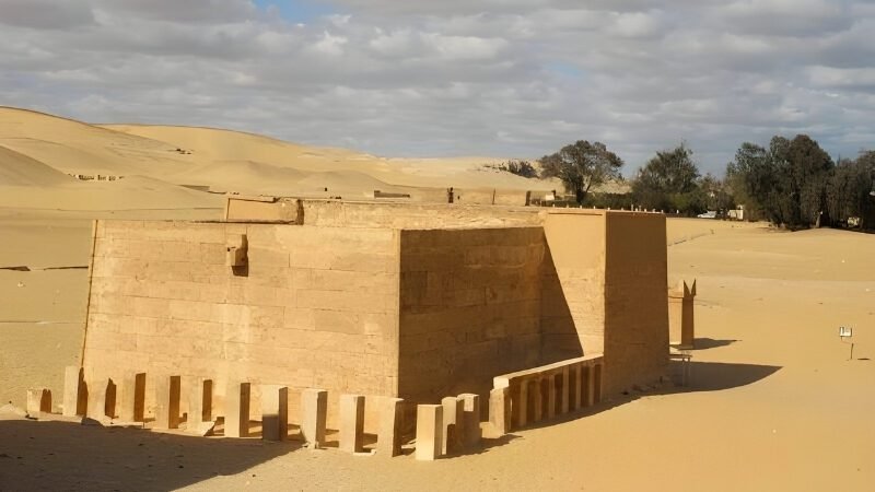 Ancient stone temple ruins under vast desert sky with scattered columns and walls
